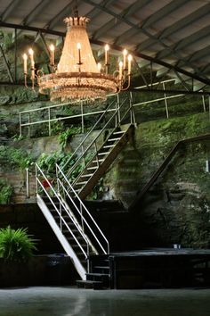 a chandelier hanging from the ceiling in a room with stone walls and stairs