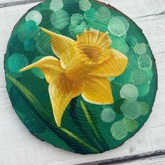 a yellow flower painted on top of a piece of wood