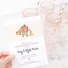 a person holding up a pink and white wedding card with gold foil straws on it