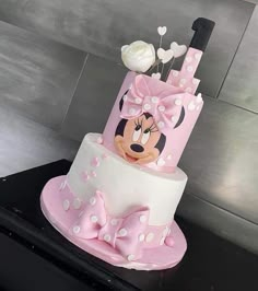 a pink and white cake with minnie mouse on top