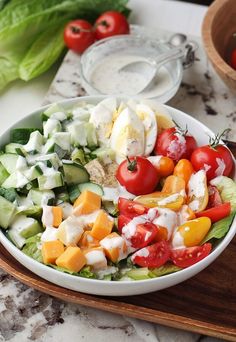 a salad with tomatoes, cucumbers, lettuce and dressing in a bowl