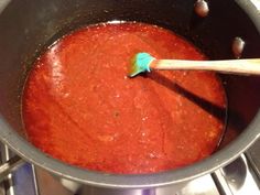 a pot filled with red sauce on top of a stove