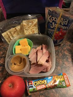 an apple, crackers, cheese, and meat in a plastic container