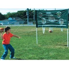 a young boy is throwing a ball to another person on the field with a net