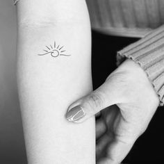 a woman's arm with a small sun tattoo on the left side of her arm