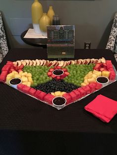 a platter filled with grapes, apples, and other fruits on top of a table