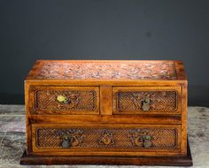 an old wooden box with carvings on the top and bottom, sitting on a table