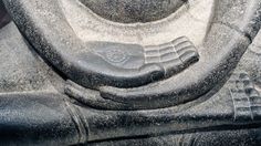 a close up of a stone statue with a hand on it's face and other symbols in the background