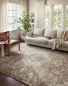 a living room filled with furniture and a rug on top of a hard wood floor