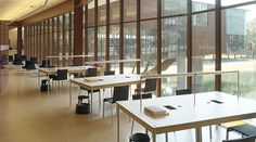 an empty room with tables and chairs in front of large windows