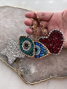 "Choose between a silver tone, gold tone or silver star clasp to complete your bag charm/keychain. Each chain comes with both a bag clasp and (removeable) keyring. Star measures 2.6\" across points Love Bomb measures 2.4\" x 2.4\" Eyes measure just under 3\"L at it's widest point Please note this item will be made when order is placed. If you would like to add/change anything please contact me prior to placing order. Any changes will be considered a custom order and may increase cost. Please not Handbag Charms Aesthetic, Bag Accessories Charm, Cheap Trendy Bag Charm, Handbag Picture Charms, Beads Bag Charm, Bag Clasp, Luxury Bag Charm With Keychain, Crystal Purse, Crystal Handbag