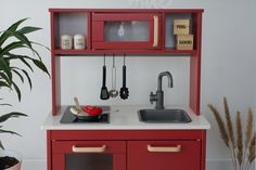 a small kitchen with red cabinets and white counter tops, including a sink and oven