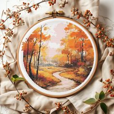 a cross stitch pattern with an autumn scene in the background and orange leaves around it