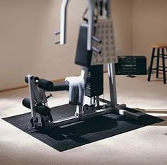 an exercise machine sitting on top of a black mat in a room with white walls