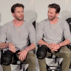 two men sitting next to each other in front of a white wall with black chairs