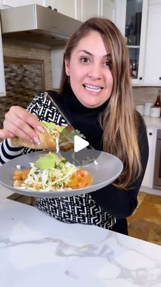 a woman holding a plate full of food in her hands and smiling at the camera