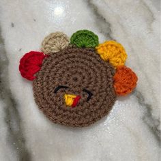 a crocheted turkey brooch with multicolored pom poms on it