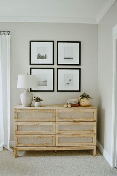 a living room with pictures on the wall and a wicker dresser in front of it