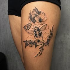 a woman's thigh with a bee and flowers tattoo on the side of her leg