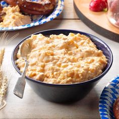 a bowl of mashed potatoes sits on a table next to other plates of food