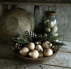 a bowl filled with mushrooms and pine cones on top of a wooden table next to a ball