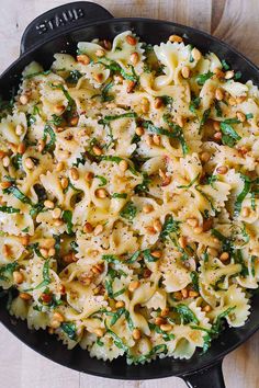 pasta with spinach and pine nuts in a black skillet on a wooden table