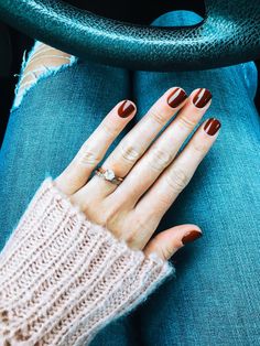 a woman's hand with brown and white nail polish on her nails sitting in a car seat