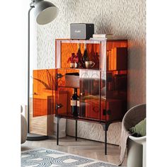 an orange cabinet with wine bottles on it in a living room next to a lamp