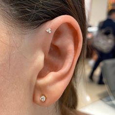 a close up of a person's ear with three diamond studs on it