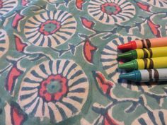 four crayons sitting on top of a flowered tablecloth next to each other