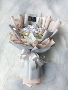 a bouquet of flowers wrapped in paper and tied with ribbon on white furnishing