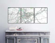 two maps are hanging on the wall above a dresser