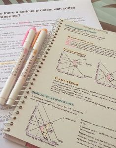 two pencils sitting on top of a notebook next to some papers with diagrams and graphs