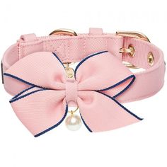 a pink dog collar with a large bow and pearl charm on it's side