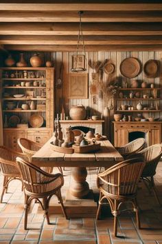 an old fashioned kitchen with wicker chairs and wooden table surrounded by baskets on the wall