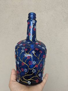 a hand holding a blue vase with red, white and blue flowers painted on it