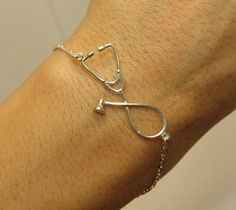 a woman's arm with a silver medical bracelet on it and a stethoscope attached to the wrist