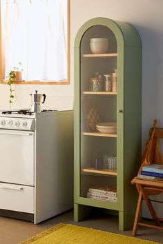 a kitchen with an oven, stove and green cabinet in the corner next to a yellow rug