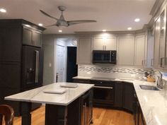 a large kitchen with an island and ceiling fan in the center, along with dark wood cabinets