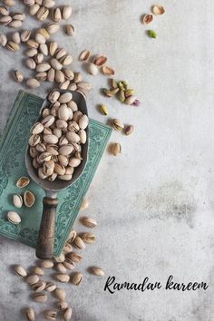 nuts spilling out of a wooden spoon onto a green towel on a white tablecloth