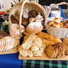 breads and pastries are displayed in baskets on a table with blue cloth draped over it