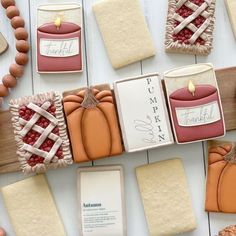 some cookies are decorated with pumpkins, candles and other items on a white table