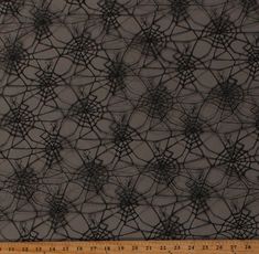 a ruler is shown next to a black and white fabric with spider webs on it