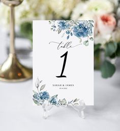 the table numbers were placed on top of each other with blue flowers and greenery