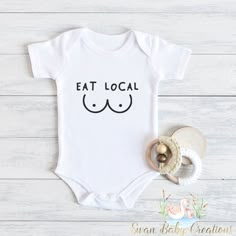 a baby bodysuit with the words eat local on it next to a pacifier