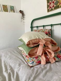 a bed topped with lots of pillows on top of it's headboard next to a wall