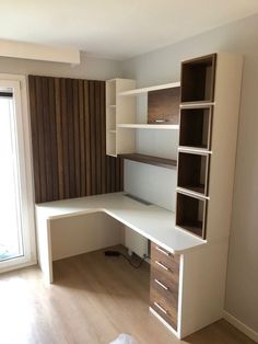 an empty room with a desk and bookcases on the wall next to a window