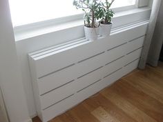 two potted plants sitting on top of a window sill next to a radiator