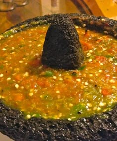 a black object is placed in the middle of a bowl filled with vegetables and sauce