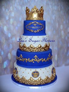 a three tiered cake with gold and blue frosting on the top, topped with a crown